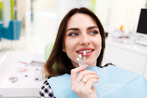 a girl choosing the color of veneers at the dentist office