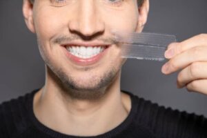 man with whitening strips next to his face