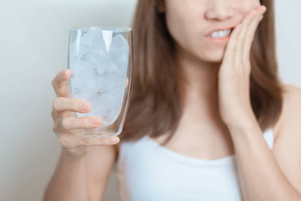 woman holding ice water glass and having toothache