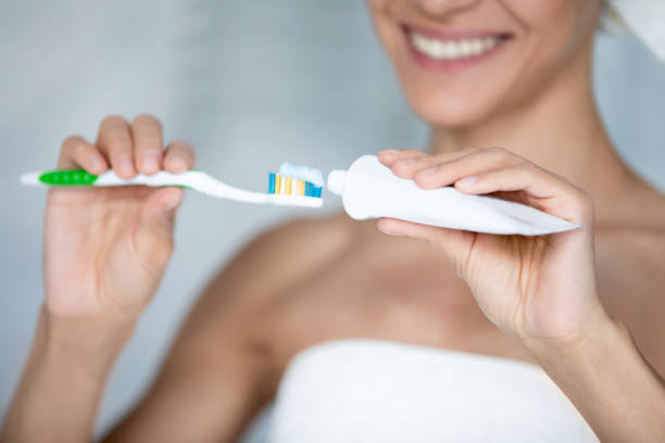 a woman applying toothpaste on her toothbrush while smiling